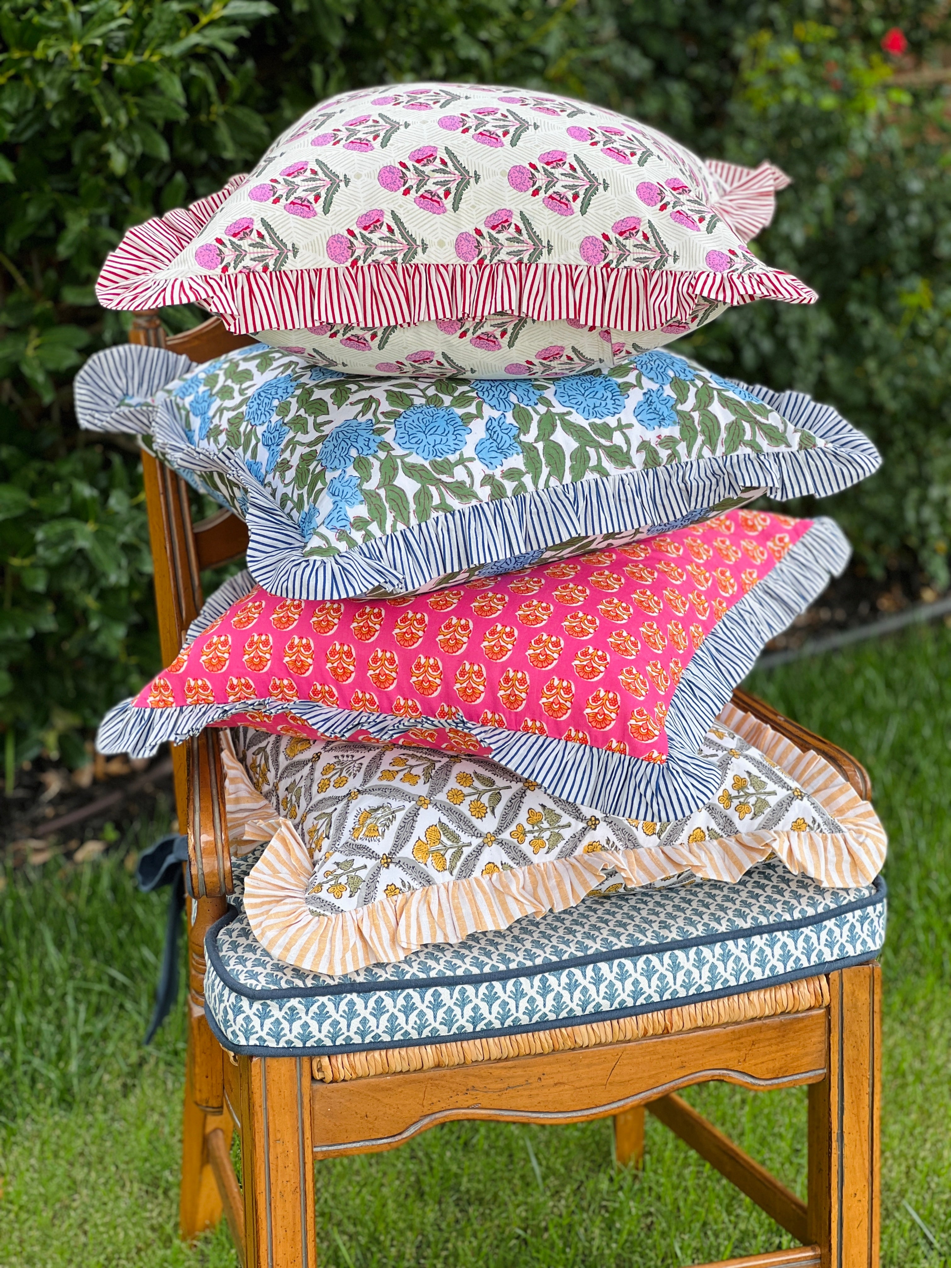 Pink and orange block print throw pillow cover with blue striped ruffle trim