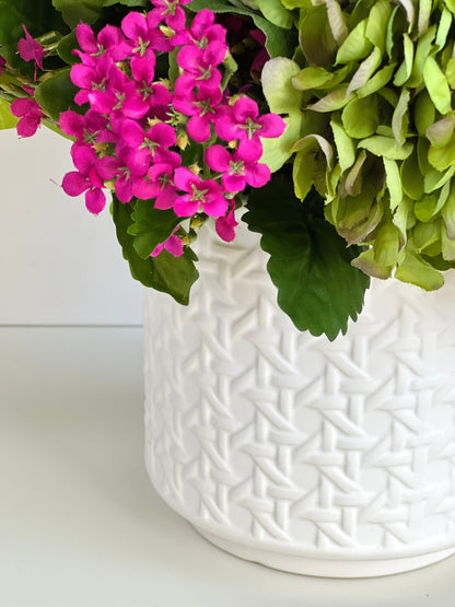 Green and fuchsia lifelike floral arrangement in white ceramic cane embossed planter