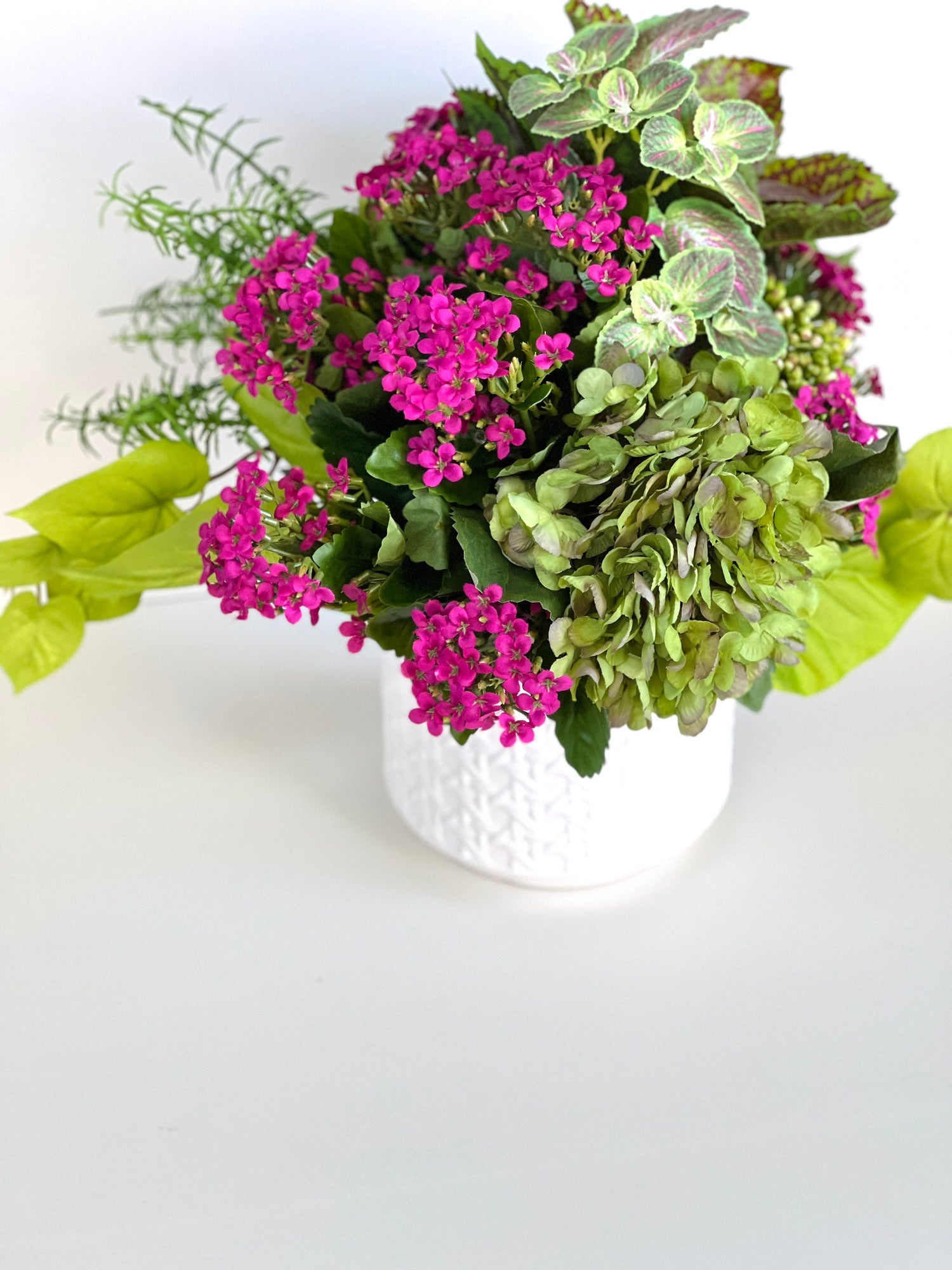 Green and fuchsia lifelike floral arrangement in white ceramic cane embossed planter