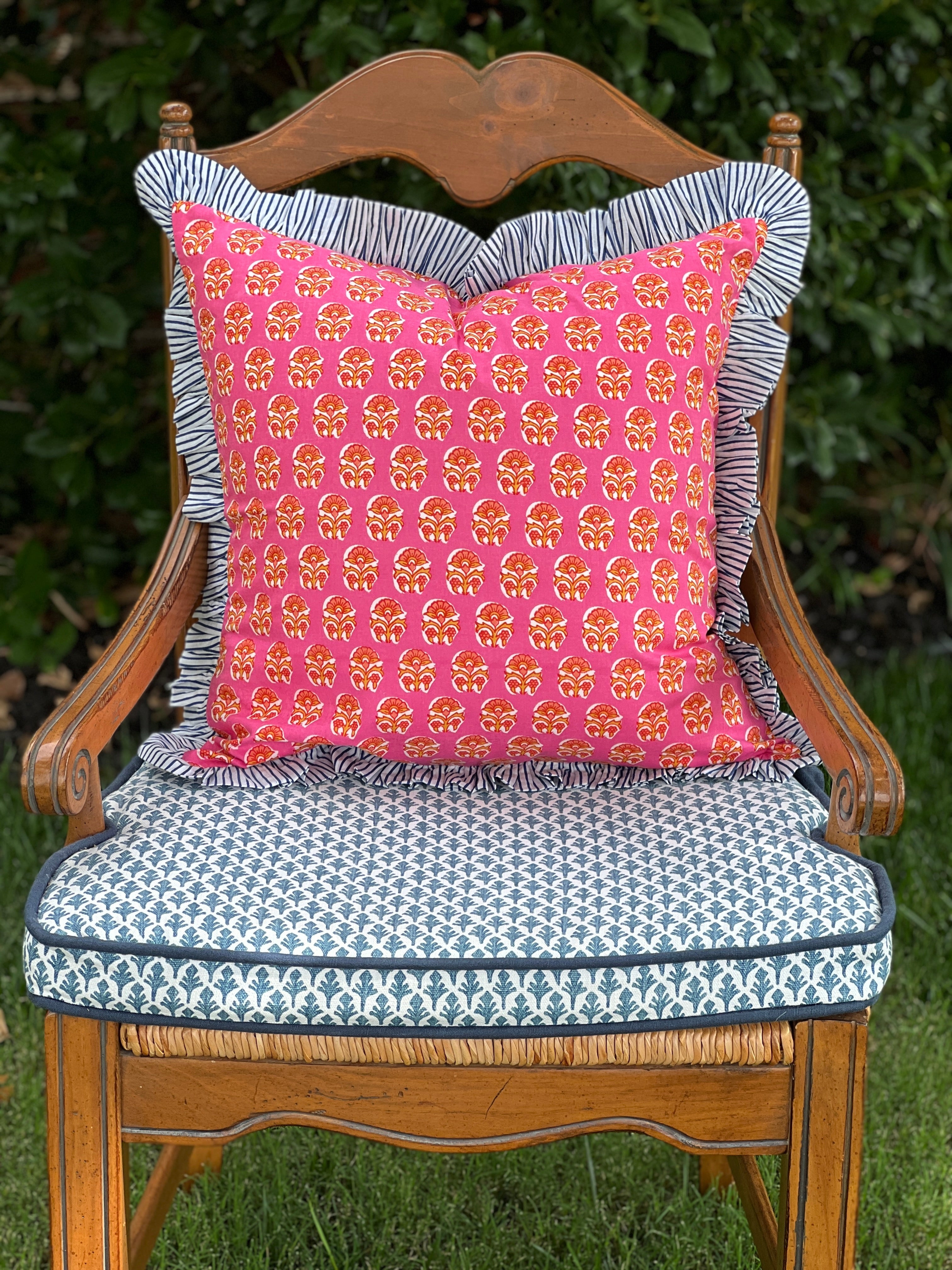 Pink and orange block print throw pillow cover with blue striped ruffle trim