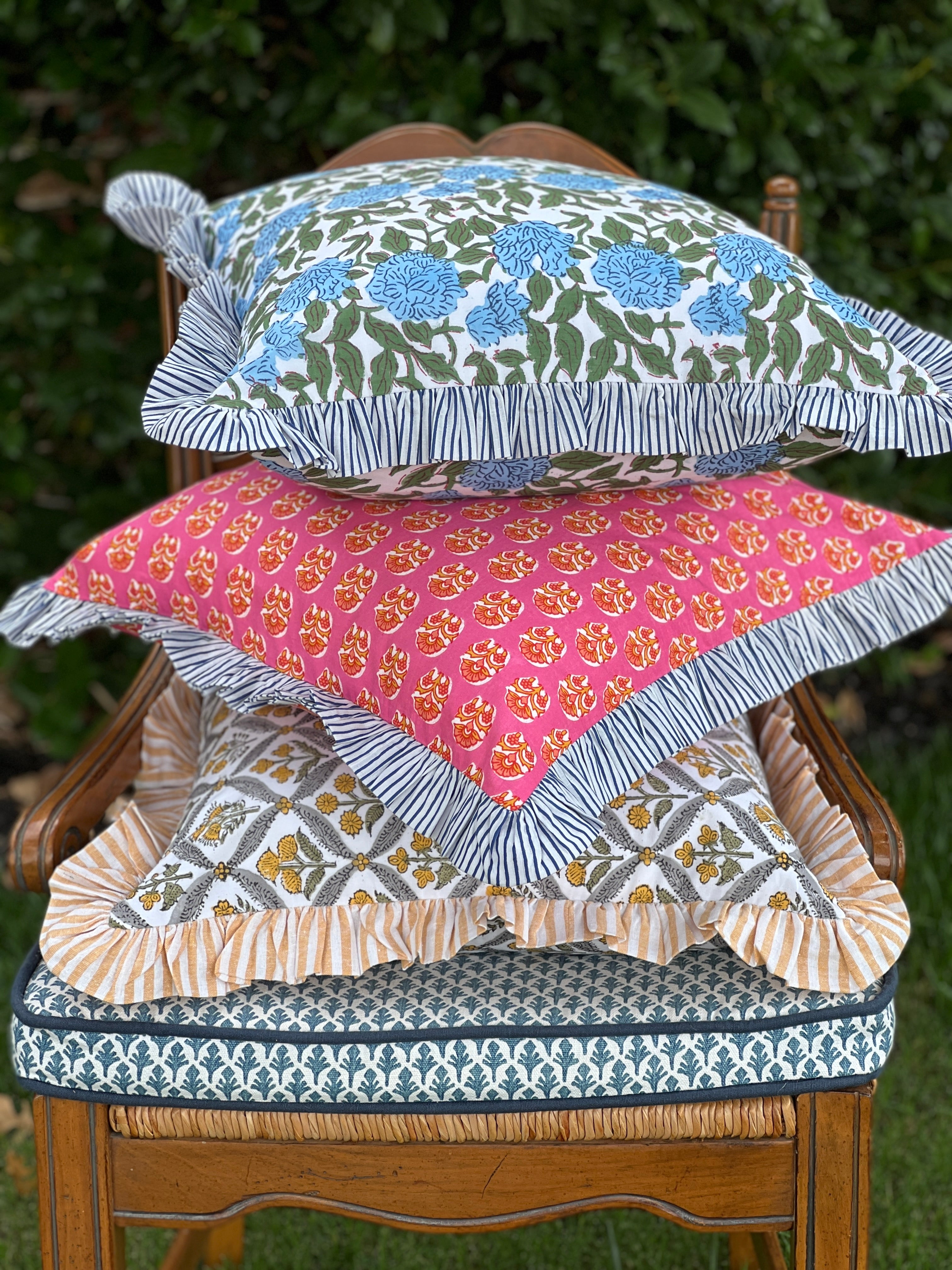 Pink and orange block print throw pillow cover with blue striped ruffle trim